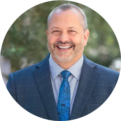 A man in a suit and tie smiling for the camera.