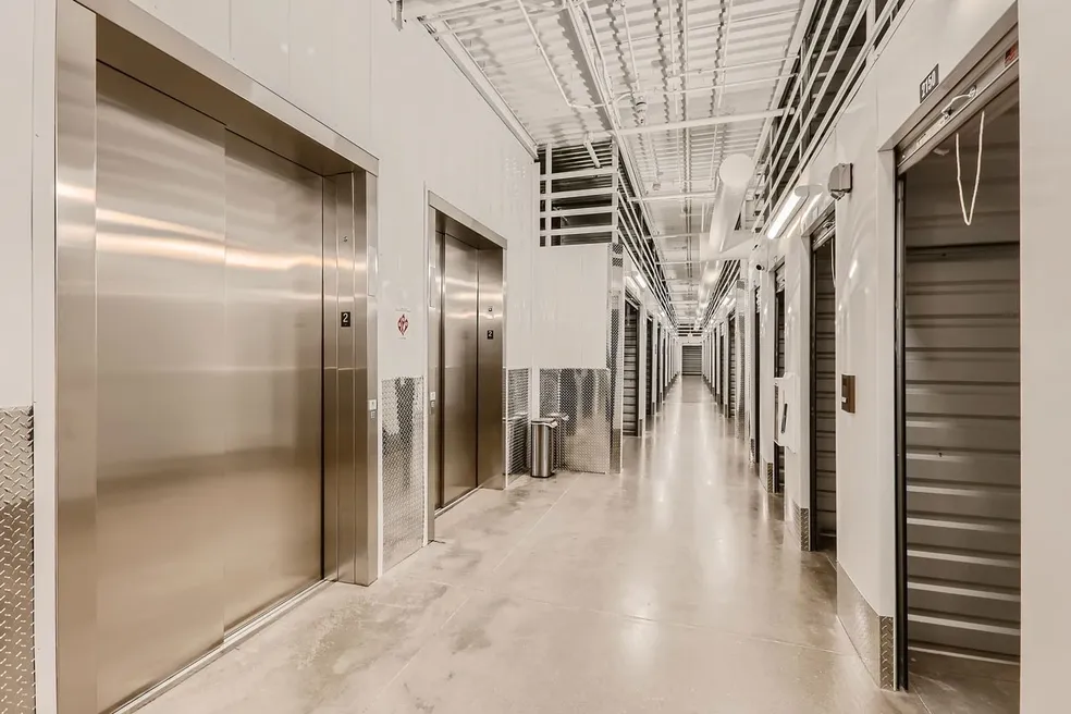 A long hallway with many doors and metal walls.