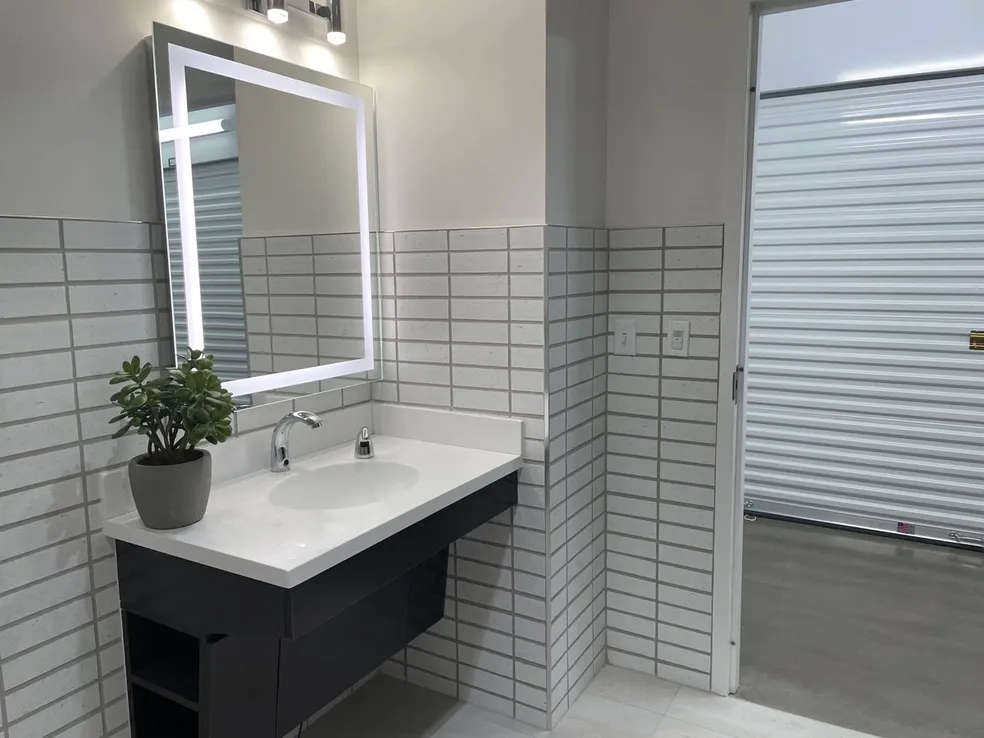 A bathroom with white tile and black cabinets.