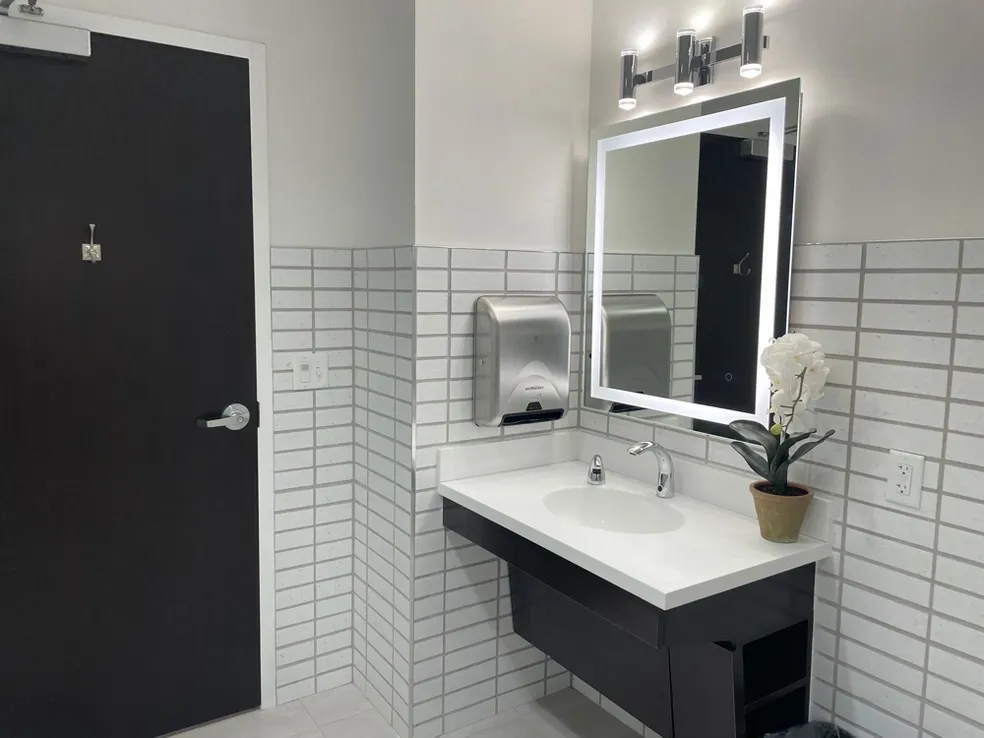 A bathroom with white tile and black cabinets.